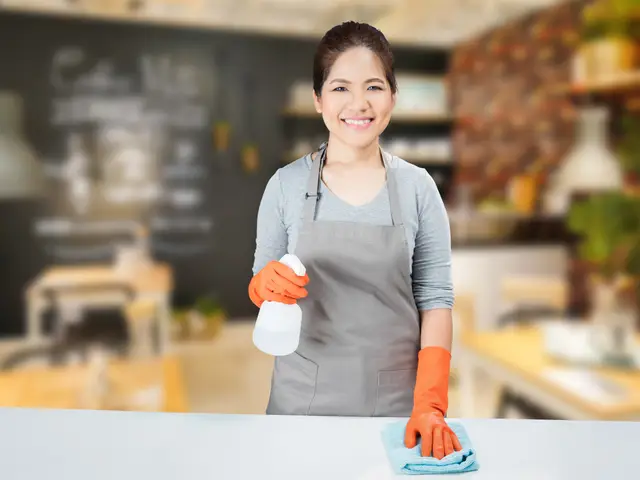 Domestic helper in an apron wiping a kitchen counter