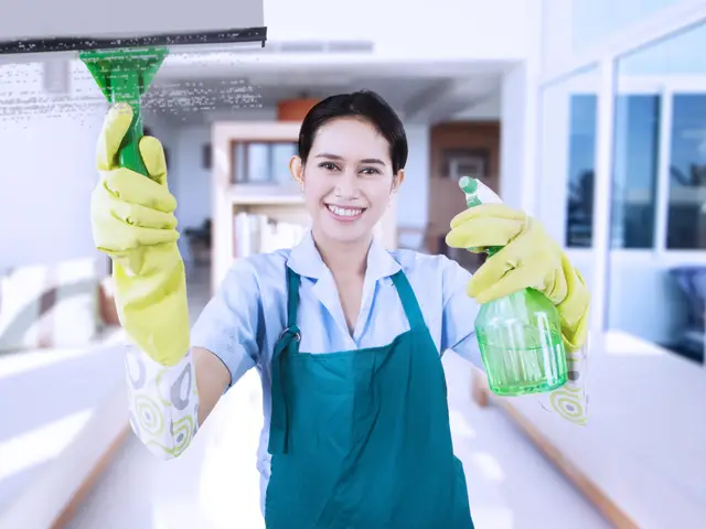 Smiling domestic helper holding cleaning tools